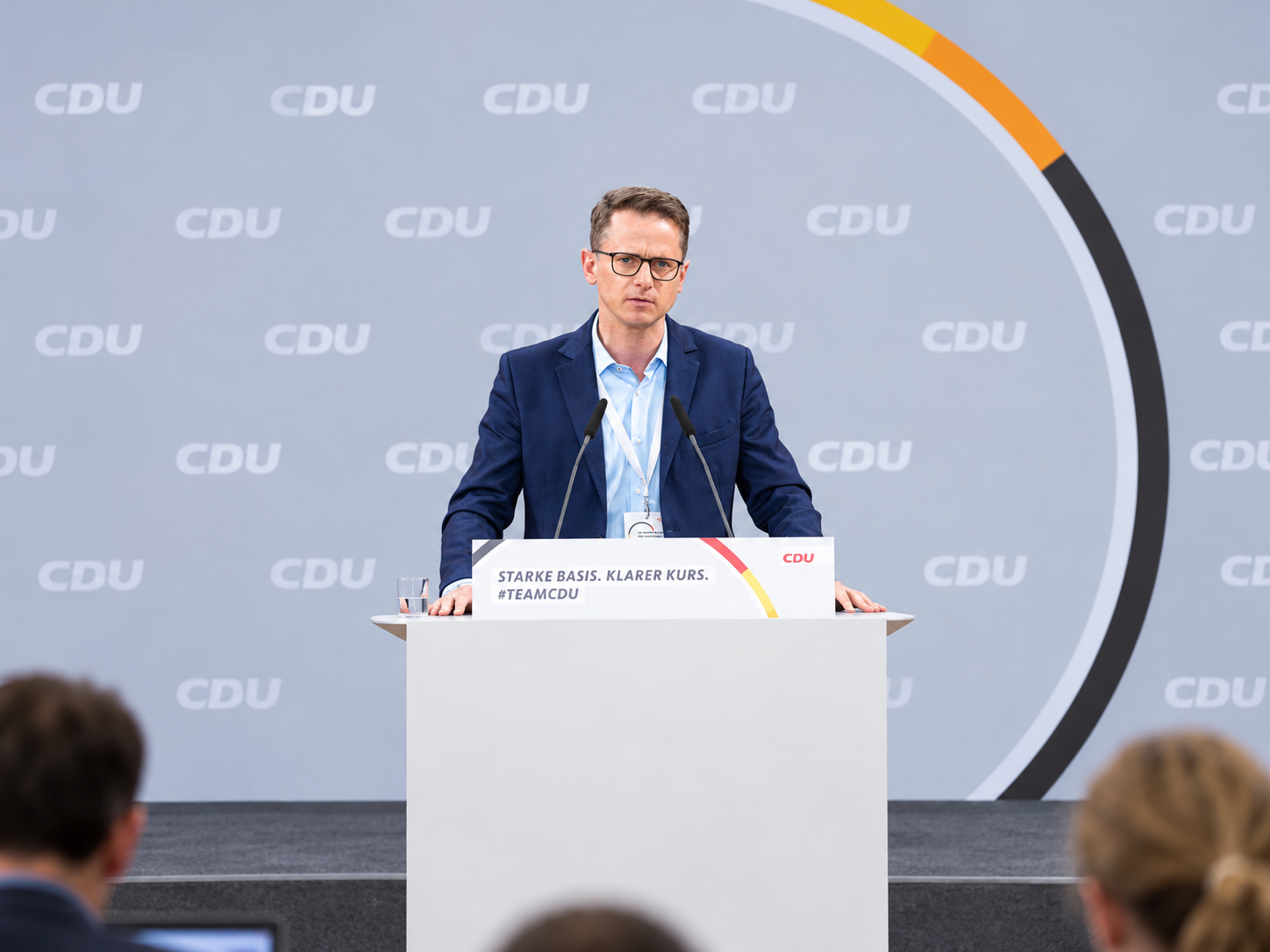 CDU-Politiker Carsten Linnemann während einer Rede auf einer Parteiveranstaltung. Als Redner steht er vor einer CDU-Kulisse. Die Aufnahme illustriert die politische Debatte über die Finanzierung des deutschen Gesundheitswesens und die drohenden Einsparungen ab 2027.